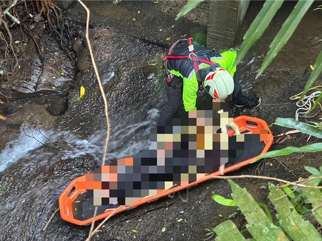 基隆市七堵区华新一路附近8日传出死亡意外，有一名民眾报警表示其患有轻微失智的岳父昨晚失踪，之后被发现已跌落5米深的排水沟，消防人员到场时发现该老翁已无生命迹象。图为消防人员将死者吊挂之情形。（基隆市消防局提供／徐佑升基隆传真）