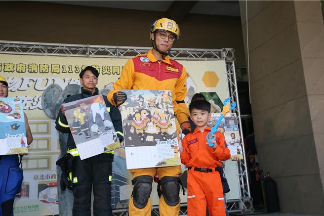 北市消防哥哥、姊姊们到场与小朋友们展示月历。（翻摄照片／林郁平台北传真）