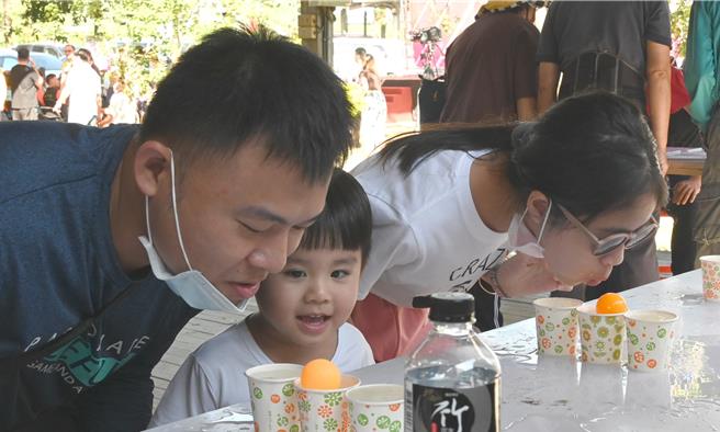 高雄大树苦瓜节活动9日登场，图为民眾参加吹水球的闯关游戏，与会者要把浮在杯子中的塑胶球吹出去才算过关，一旁的小朋友跃跃欲试。（林瑞益摄）