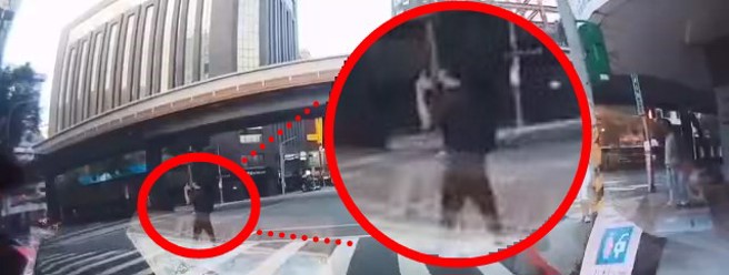 黑衣男子闯红灯过马路，边跳舞还比中指。（翻摄爆料公社）