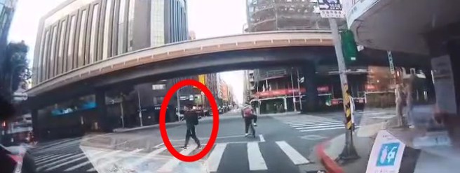 黑衣男子闯红灯过马路，边跳舞还比中指。（翻摄爆料公社）