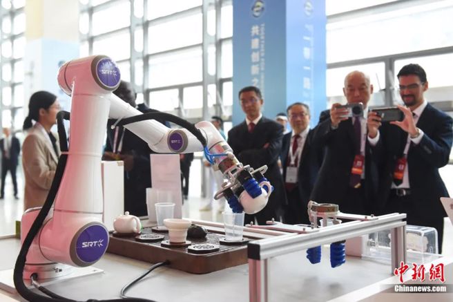 首届「一带一路」科技交流大会现场的智慧茶艺机器人吸引嘉宾观看。（中新网）