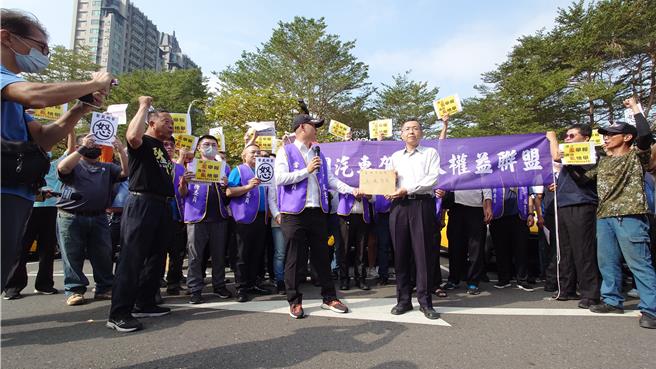 上百名駕駛人集結高美館抗議政府交通政策，全國汽車駕駛人權益聯盟活動召集人林竑江（左前）向高雄市交通局由專委黃信穎（右前）遞交陳情書。（任義宇攝）