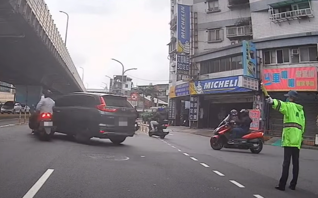 有骑士因要抢快上桥，直接违规行驶，下秒撞车倒地，一旁指挥交通的义交，看了好气又无奈。（ 图／ 翻摄自「WoWtchout-地图型行车影像分享平台」）