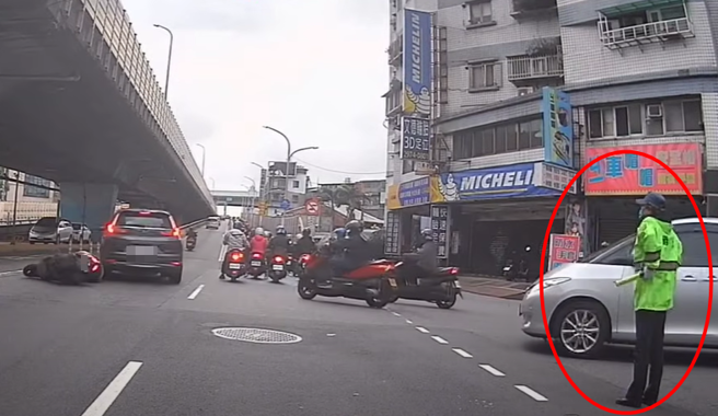 有骑士因要抢快上桥，直接违规行驶，下秒撞车倒地，一旁指挥交通的义交，气到都手插腰了。（ 图／ 翻摄自「WoWtchout-地图型行车影像分享平台」）