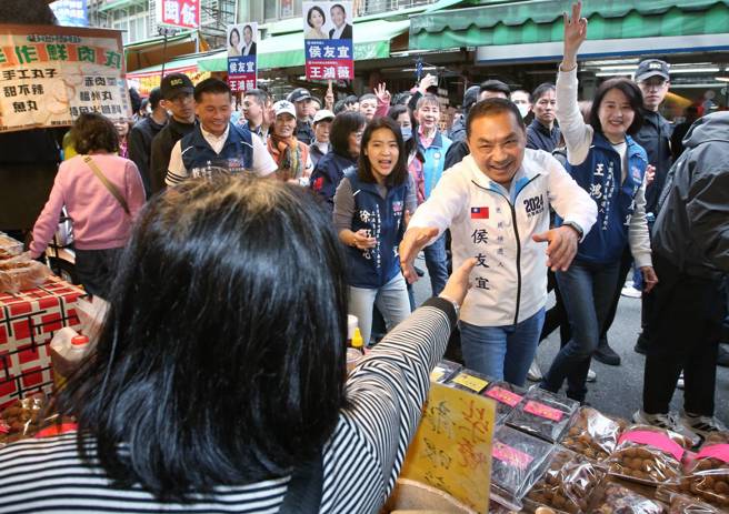 國民黨總統候選人侯友宜（右前）16日到台北市南京公寓市場掃街拜票，受到攤商熱烈歡迎。（趙雙傑攝）