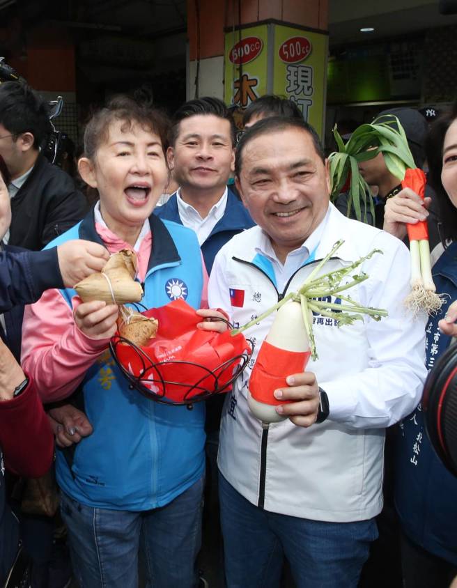 國民黨總統候選人侯友宜（右前）16日到台北市南京公寓市場掃街拜票，受到攤商熱烈歡迎，有人送上好彩頭和粽子，祝他高票當選。（趙雙傑攝）