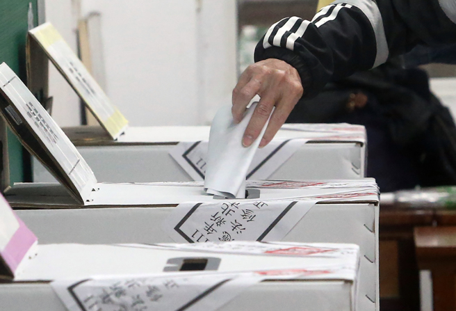 圖為去年九合一大選，民眾將圈好的選票投入票匭。（資料照,趙雙傑攝）