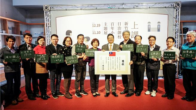 新竹县史馆19日「上课钟响 - 新竹县日治创校百年小学主题展」，县长杨文科（右六）扮校长，请百年小学校长回答设校时间后颁给「奖状」。（罗浚滨摄）