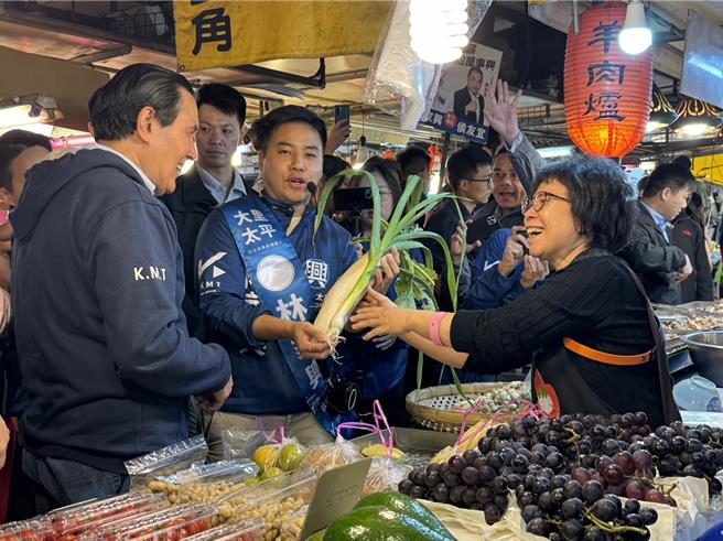 距離2024大選不到1個月，馬英九前總統（左）19日下午在台中七選區立委參選人林家興（中）陪同下前往大里區內新市場拜票，攤商送上菜頭祝福。（潘虹恩攝）