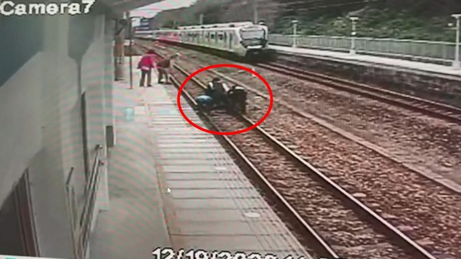 4人合力要拉男子离开铁道，男子奋力抵抗。（翻摄画面）