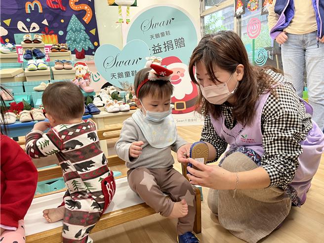 勢角公托中心主任游怡文幫小朋友穿上天鵝鞋。（新北市社會局提供）