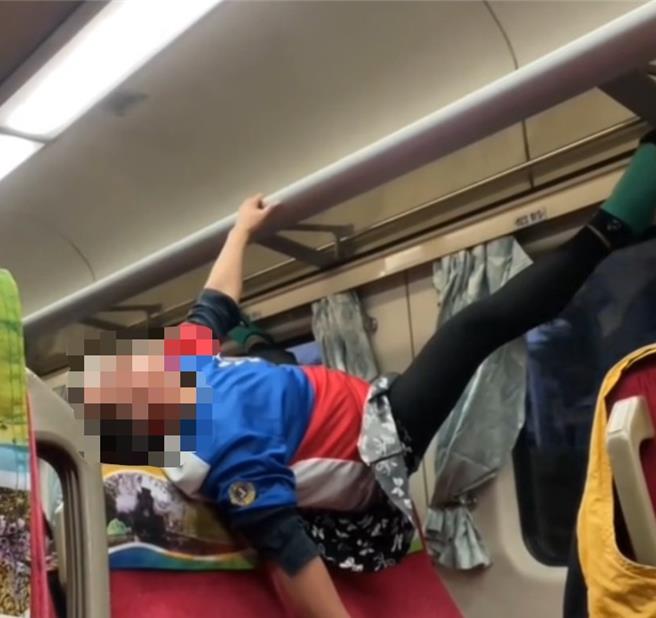 張姓女乘客21日傍晚搭乘台鐵莒光號521車次時，竟在車廂內吊掛在置物架上做體操。（翻攝照片／蔡明亘桃園傳真）