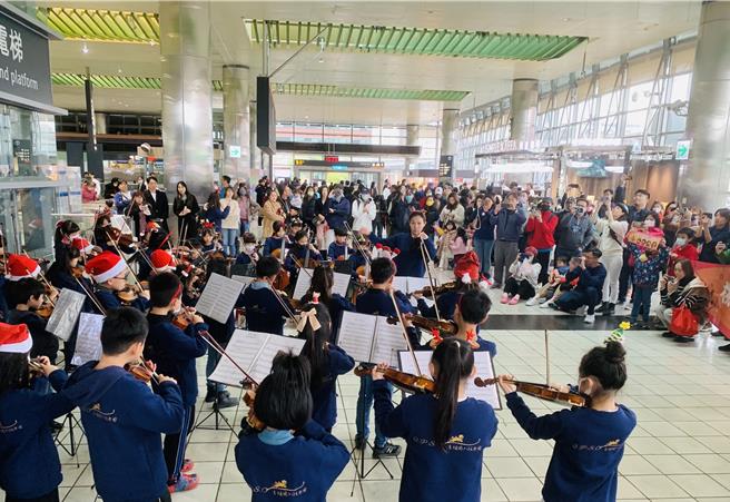 桃园市青埔国小弦乐团23日下午在高铁桃园站快闪演出，与乘客欢庆耶诞佳节。（台湾高铁提供／蔡明亘桃园传真）