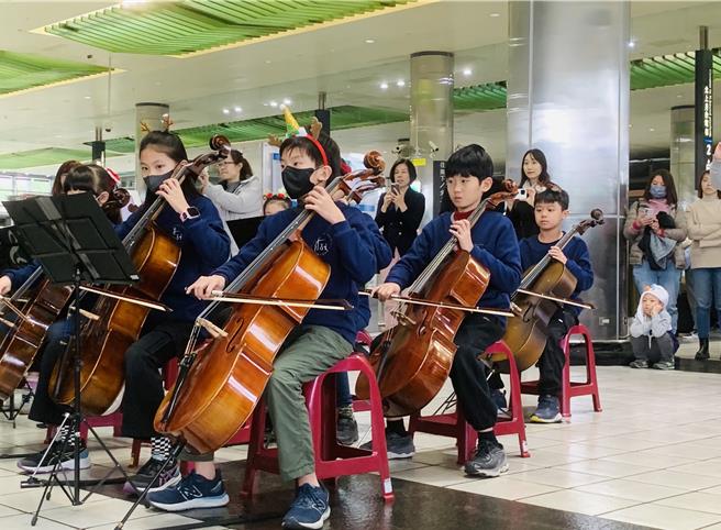 桃园市青埔国小弦乐团23日下午在高铁桃园站快闪演出，与乘客欢庆耶诞佳节。（台湾高铁提供／蔡明亘桃园传真）