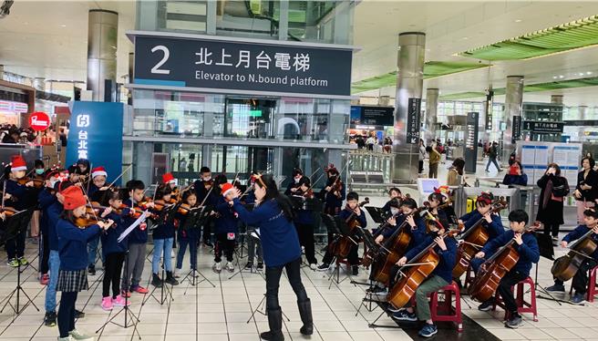 桃园市青埔国小弦乐团23日下午在高铁桃园站快闪演出，与乘客欢庆耶诞佳节。（台湾高铁提供／蔡明亘桃园传真）
