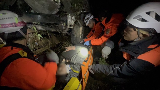 坠谷箱型车车体扭曲变形，搜救人员漏夜抢救，用油压剪破坏车体，救出受困车内患者送医。（民眾提供／杨静茹南投传真）