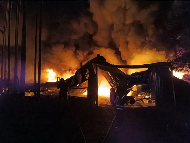 南投縣魚池鄉大林村一處香菇寮暗夜大火，鐵皮均坍塌，消防員布水線灌救。（南投縣消防局提供／楊靜茹南投傳真）