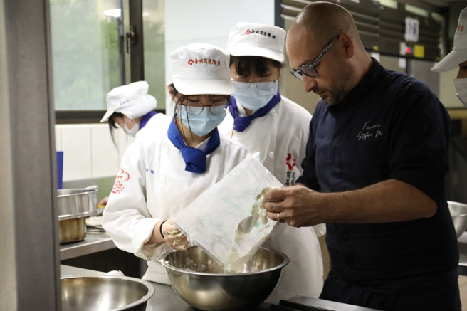 Stefan主廚非常喜愛與同學們互動，逐一到各個餐台觀察同學製作的過程，適時地給予指導。(照片/育達高中提供)
