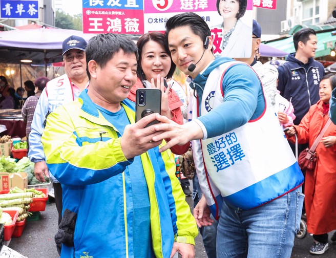 台北市長蔣萬安（右）30日一早陪同國民黨立委候選人王鴻薇（中）赴濱江市場拜票，兩人所到之處受到民眾熱烈歡迎，不時有上街買菜的粉絲要求自拍。（粘耿豪攝）