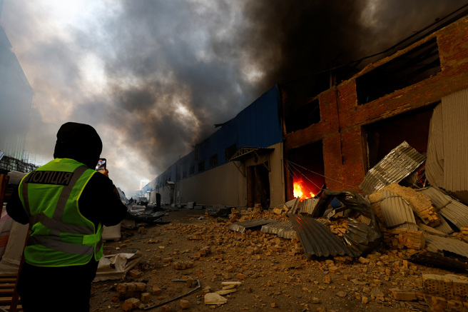 2023年12月29日，在烏克蘭基輔，一個人拍攝了因俄羅斯襲擊而嚴重受損的倉庫的照片。（路透社）