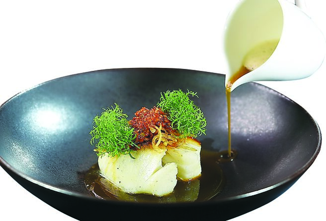 〈A Cut〉本季「季节鲜鱼」是选用又称白鳕的小鳞犬牙南极鱼小火慢煎，肉质细致、口感滑嫩且富含胶质。提味酱汁是以青龙辣椒、墨西哥辣椒、黑橄榄及乾葱碎发酵五天制成的剁椒酱，再与发酵红辣椒酱充分混合制成的创新剁椒酱制作。图／姚舜