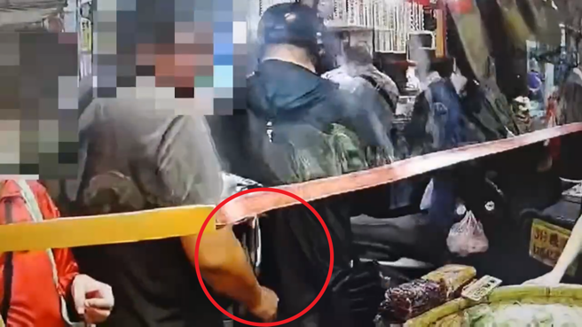 刘男在市场摊位前，下手行窃民眾背包内的皮夹。（翻摄画面）
