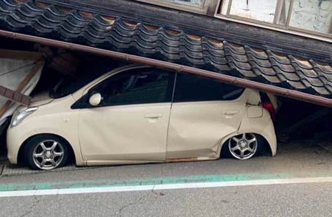 日本石川縣大地震，汽車被困在倒塌的房屋。(美聯社)