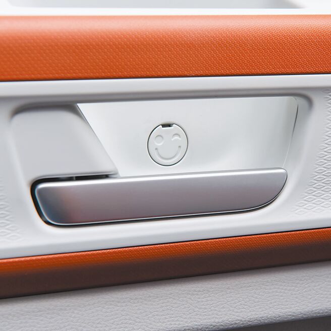 车内多处藏有幽默图案，如车门把上方螺丝孔盖有眨眼笑脸。（台湾福斯商旅提供）