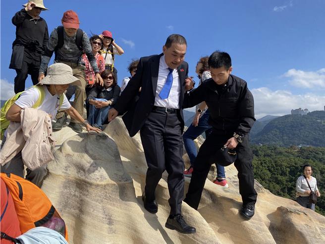 侯友宜（右二）由維安人員攙扶，慢步走下軍艦岩。（王爵暐攝）