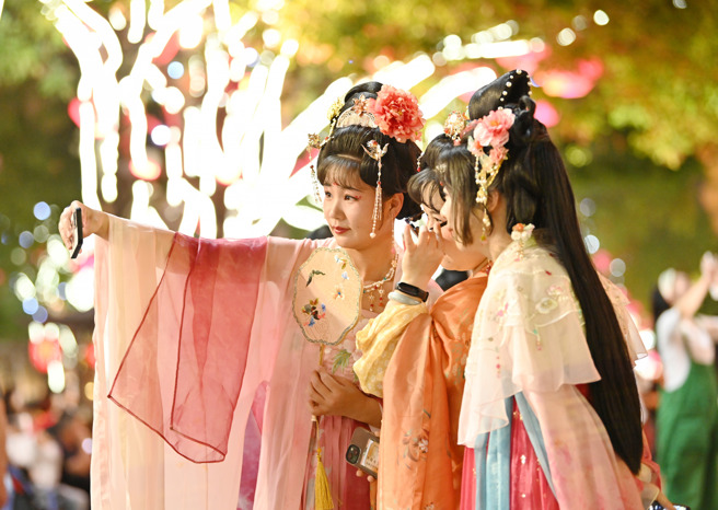 大陸網紅隨機攔人對詩，近日找到一位西安姑娘反應超快，在網路上引起討論。圖為身著古裝的遊客在西安大唐不夜城遊覽拍照。（示意圖／新華社）