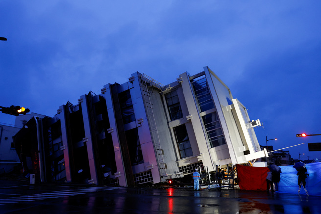 日本石川县轮岛市一栋楼房因强震倒塌。救灾人员3日持续在现场救援。（路透）