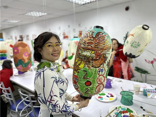 越南的武氏容和女儿一起在灯笼画上生动的神龙和恐龙，希望「2024年好运龙龙来」。（陈慰慈摄）