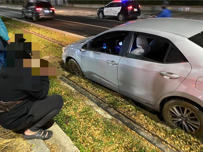 银色轿车闯入轻轨轨道后，轮胎陷入草皮受困，影响逆行轻轨列车运行44分钟，影响期间轻轨列车C23龙华国小站至C29树德家商间路段改採公车接驳。（捷运警察队提供／任义宇高雄传真）