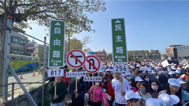 民進黨支持者展現創意，6日高舉自製「民主路」、「自由路」、「民主禁止左右轉」、「民主禁止迴轉」等路標手舉牌，上面更寫有「新竹專屬投票密碼」的256、817，期許台灣在自由民主的路上，持續穩健地走下去。（陳育賢攝）
