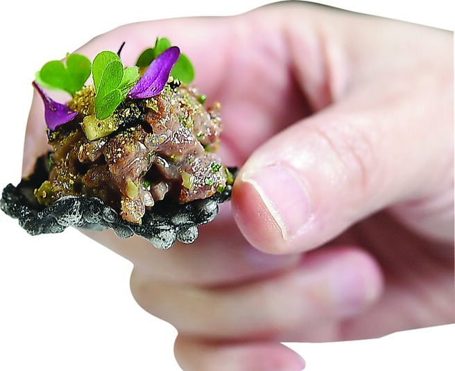 〈鹿肉塔塔／鯷魚／牛肝菌〉的脆餅是墨魚汁與西谷米製成，內餡鹿肉塔塔以鯷魚蛋黃醬、烏梅醬和牛肝菌粉提味增香。圖／姚舜