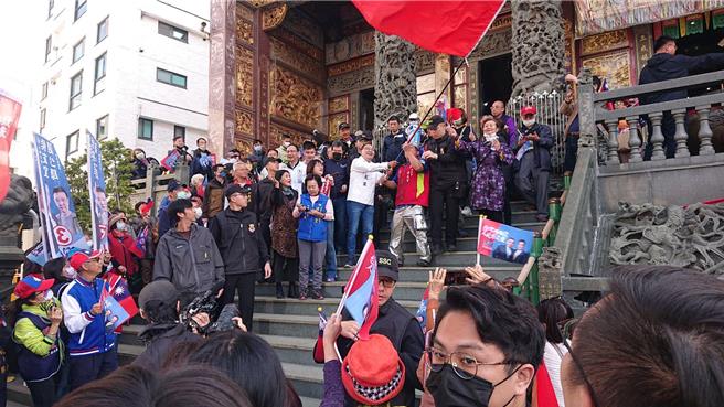 國民黨總統候選人侯友宜（階梯上白衣者）8日到台南市北區勝安宮參拜，並揮舞支持者的巨大國旗。（程炳璋攝）