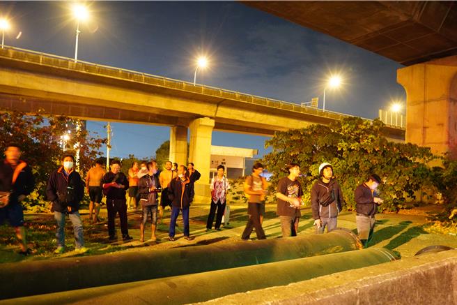 现场逃出将近30名移工，被移置到一旁的桥墩下方等待，所有人看起来均无大碍，不少移工还拿出手机拍照。（民眾提供／吴建辉彰化传真）