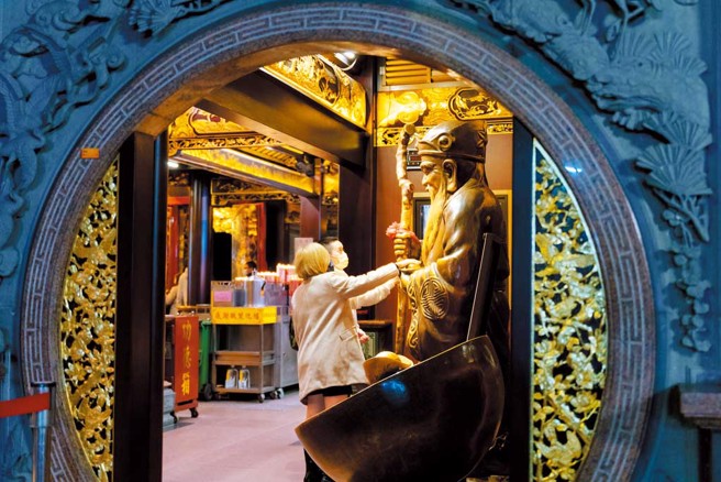 烘炉地南山福德宫庙内铜铸土地公手中的金元宝被信徒摸得闪闪发亮，还能换钱母，将硬币投入土地公手中的金元宝，祂的袖口就会掉下一枚母钱，用以增生钱滚钱。（图／新北市民政局提供）