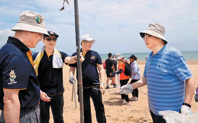 日月光环保永续基金会执行长汪渡村（右一）携手内政部警政署黄明昭（左一），在福隆海水浴场捡拾沙滩上的垃圾。（图／日月光环保永续基金会提供）