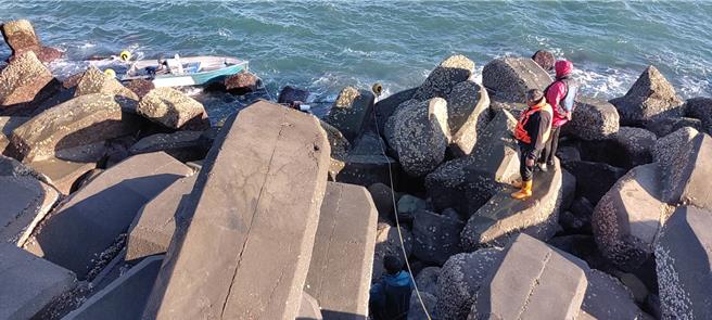 台中港13日上午驚傳船隻翻覆，4名釣客受困消波塊，海巡及消防人員馳援現場，順利將4人引導上岸。（民眾提供／王煌忠台中傳真）