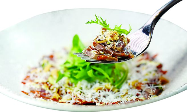 〈油封鸭胗〉是将鸭胗用鸭油低温浸泡，俟入味并软化后切片，再以发酵辣椒酱、花生碎、京水菜搭配，并现刨帕玛森起司出菜上桌。图／姚舜