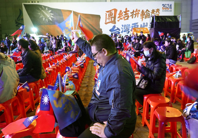 民眾顶着寒风低头看着手机中的开票过程。（姚志平摄）