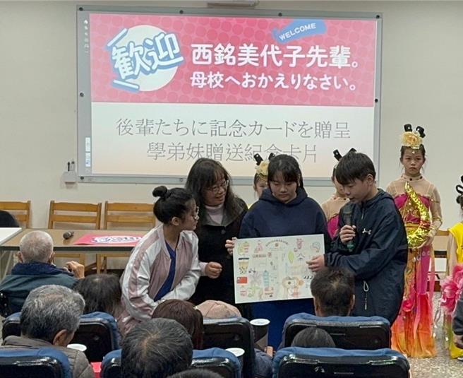 现年90岁的「西铭美代子」女士，回基隆到幼时居住地和平岛与母校正滨国小巡礼，与校方和小学弟妹们交流。图为正滨国小同学送自制卡片给西铭女士。（基隆市教育处提供／徐佑升基隆传真）