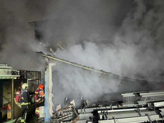 2層鐵皮建築的鴿舍遭惡火吞噬崩塌，消防隊在現場搶救中。（翻攝畫面）