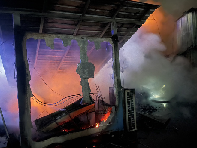 2層鐵皮建築的鴿舍遭惡火吞噬崩塌，消防隊在現場搶救中。（翻攝畫面）