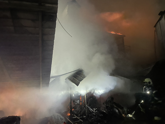 2層鐵皮建築的鴿舍遭惡火吞噬崩塌，消防隊在現場搶救中。（翻攝畫面）