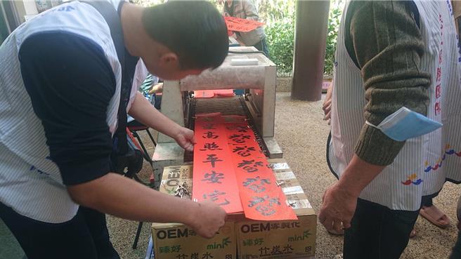 台南市北區光武里活動中心21日舉辦贈春聯活動，現場還有烘乾機便利烘乾剛書寫的春聯。（程炳璋攝）