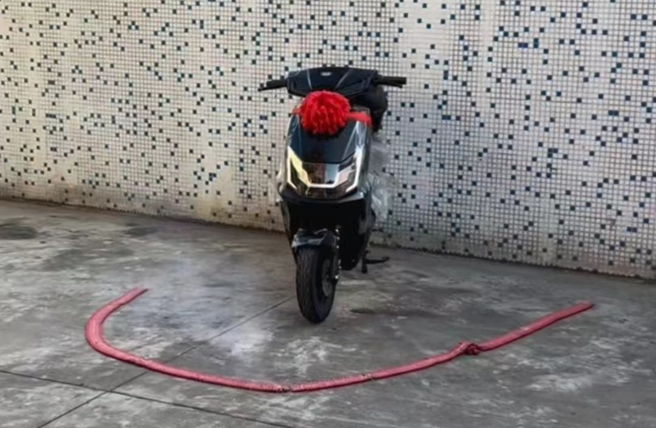 新购入电摩托车的车主十分开心，挂上彩球，准备点个鞭炮庆贺。（图／快科技）