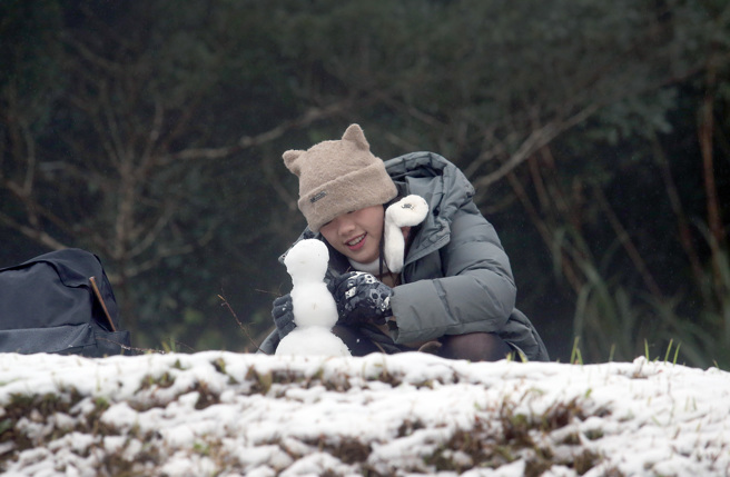 入冬最强寒流来袭，许多民眾今天（23日）前往阳明山赏雪，并开心地在雪地中堆起雪人。（范扬光摄）